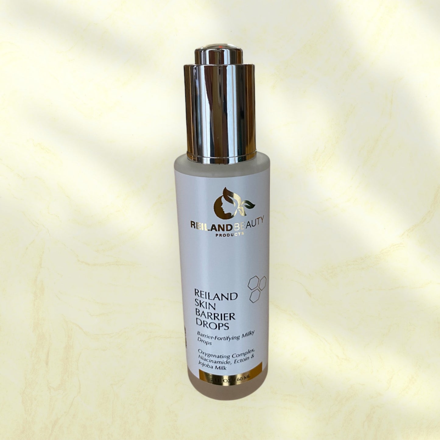 Reiland Skin Barrier Drops skincare serum on a luxurious gold marble background, emphasizing its hydrating, barrier-fortifying, and skin-rejuvenating benefits. Infused with Niacinamide, Ectoin, and Jojoba Milk to restore hydration, reduce redness, and enhance skin radiance. Ideal for all skin types.