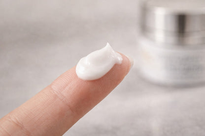 Close-up of a fingertip holding a smooth, creamy skincare texture from the Reiland Advanced Age Reverse System, shown against a soft neutral background to highlight consistency and application feel.