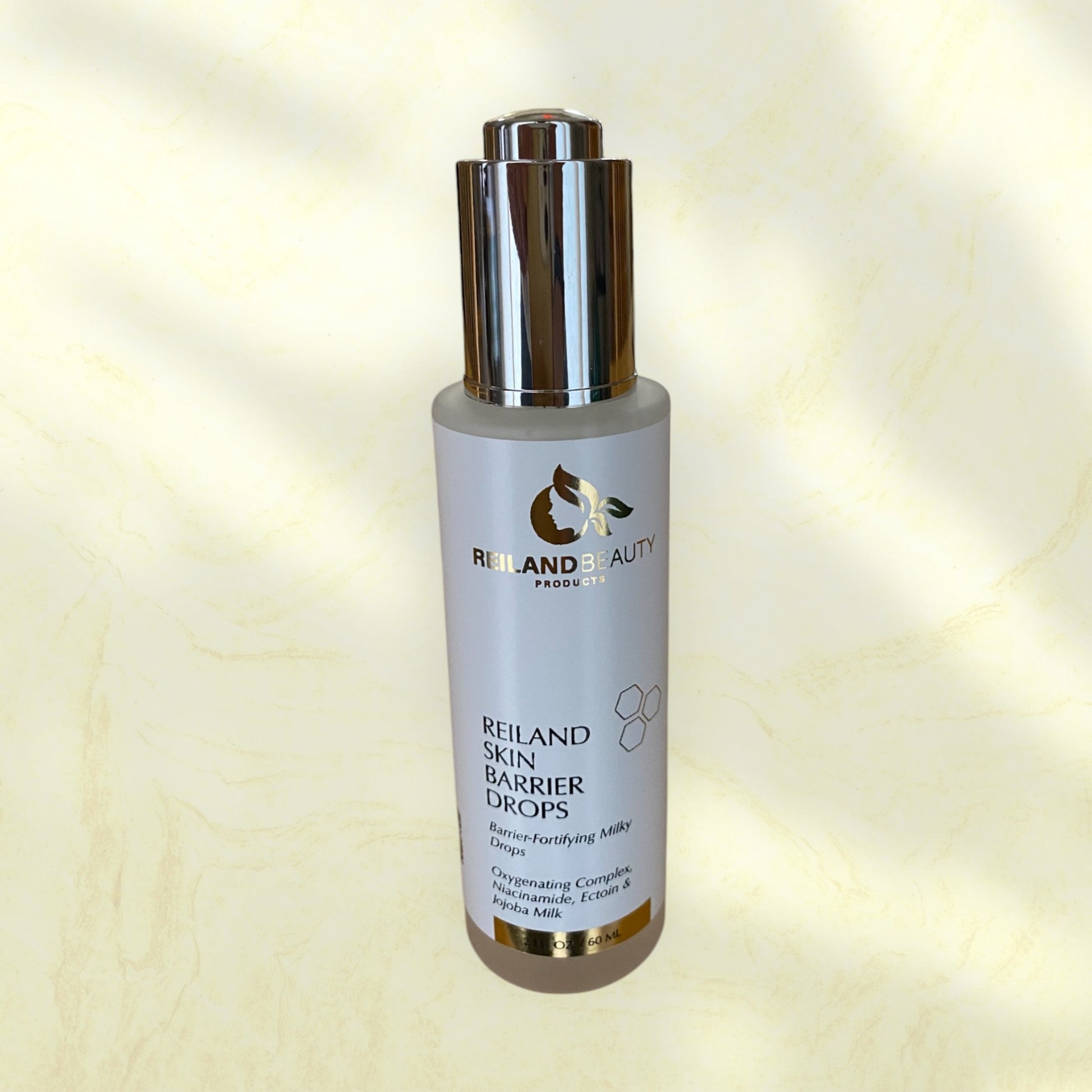 Reiland Skin Barrier Drops skincare serum on a luxurious gold marble background, emphasizing its hydrating, barrier-fortifying, and skin-rejuvenating benefits. Infused with Niacinamide, Ectoin, and Jojoba Milk to restore hydration, reduce redness, and enhance skin radiance. Ideal for all skin types.