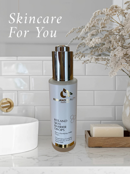 Reiland Skin Barrier Drops skincare serum displayed in a luxury bathroom setting with white subway tiles, marble countertops, and elegant dried florals. A hydrating, barrier-fortifying serum with Niacinamide, Ectoin, and Jojoba Milk, designed to restore skin balance, reduce redness, and enhance radiance. Ideal for all skin types.