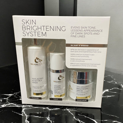 Front view of Reiland Advanced Skin Brightening System featuring cleanser, calming serum, and vitamin C brightening cream in boxed packaging. Positioned on a black marble surface with clear product claims highlighting improvements in skin tone, luminosity, and fine lines within 6 weeks.