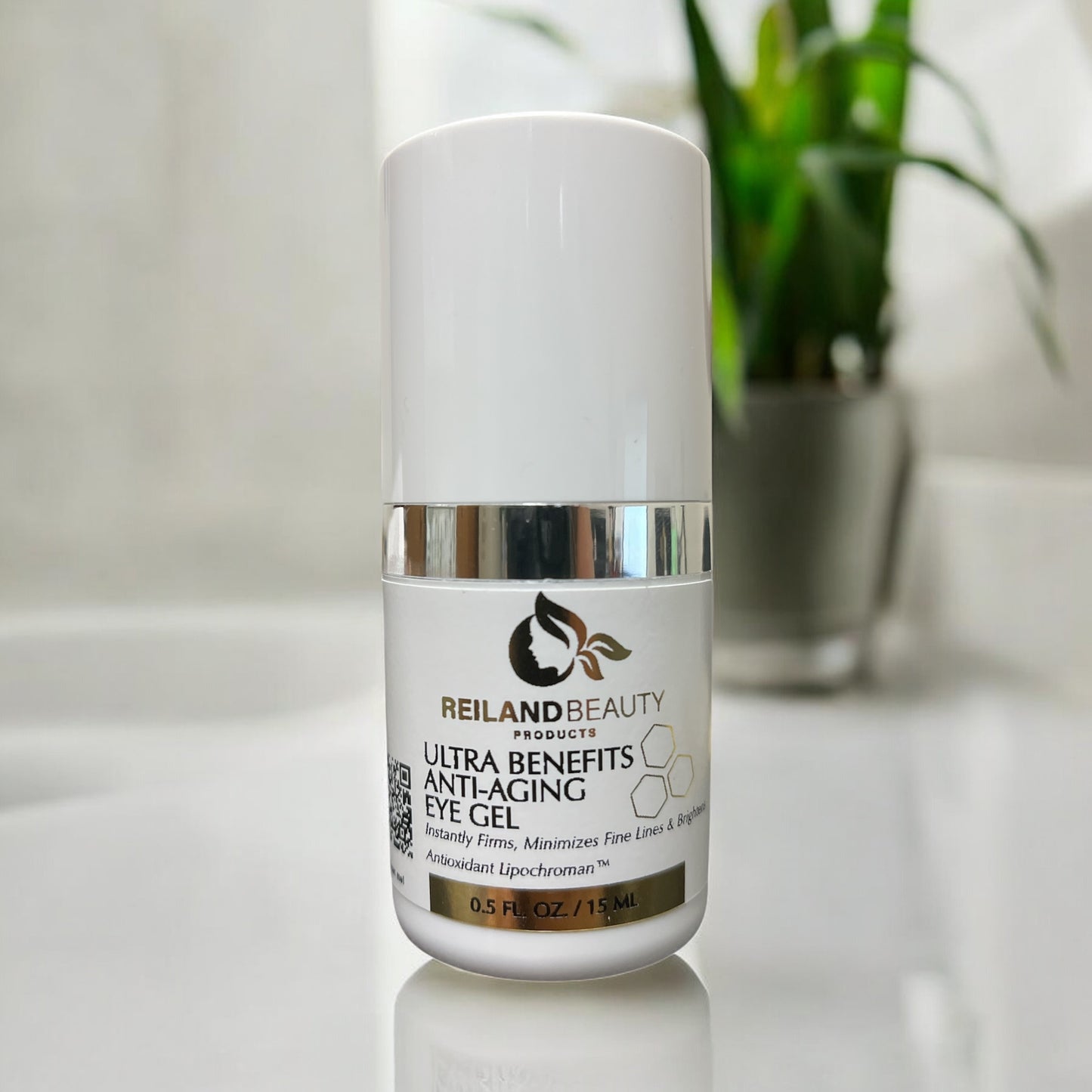 Reiland Anti-Aging Eye Gel standing on a reflective white counter with a blurred green plant in the background, showcasing freshness and skincare purity.