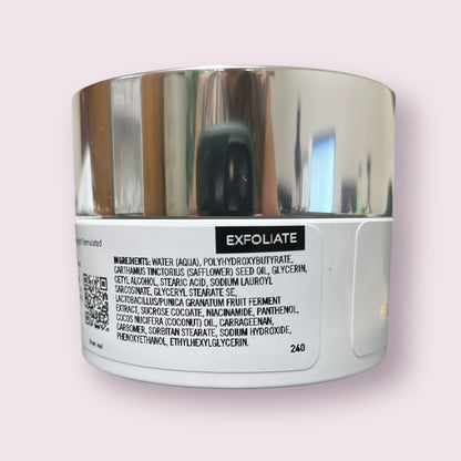 Rear view of Reiland Vitamin B Hydrating Scrub container featuring detailed ingredient list including water, niacinamide, panthenol, and pomegranate ferment, displayed on a soft pink background.