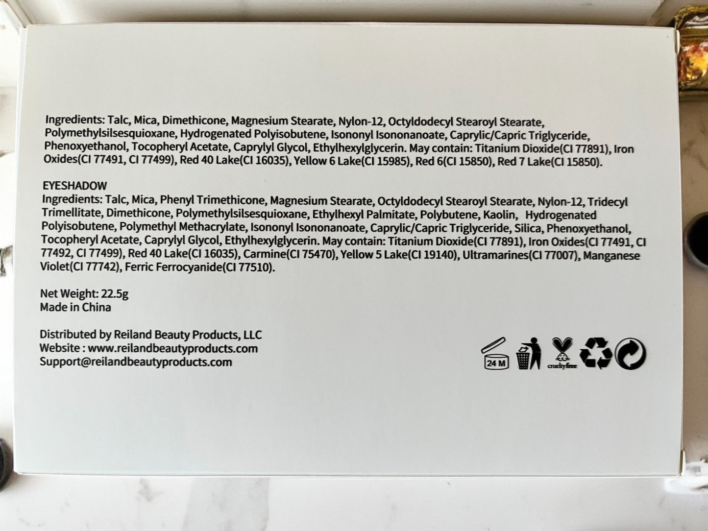 Back of Velvet Bloom eyeshadow palette box showing full ingredients list, product weight, cruelty-free and recycling icons, and Reiland Beauty Products contact information on a white background.
