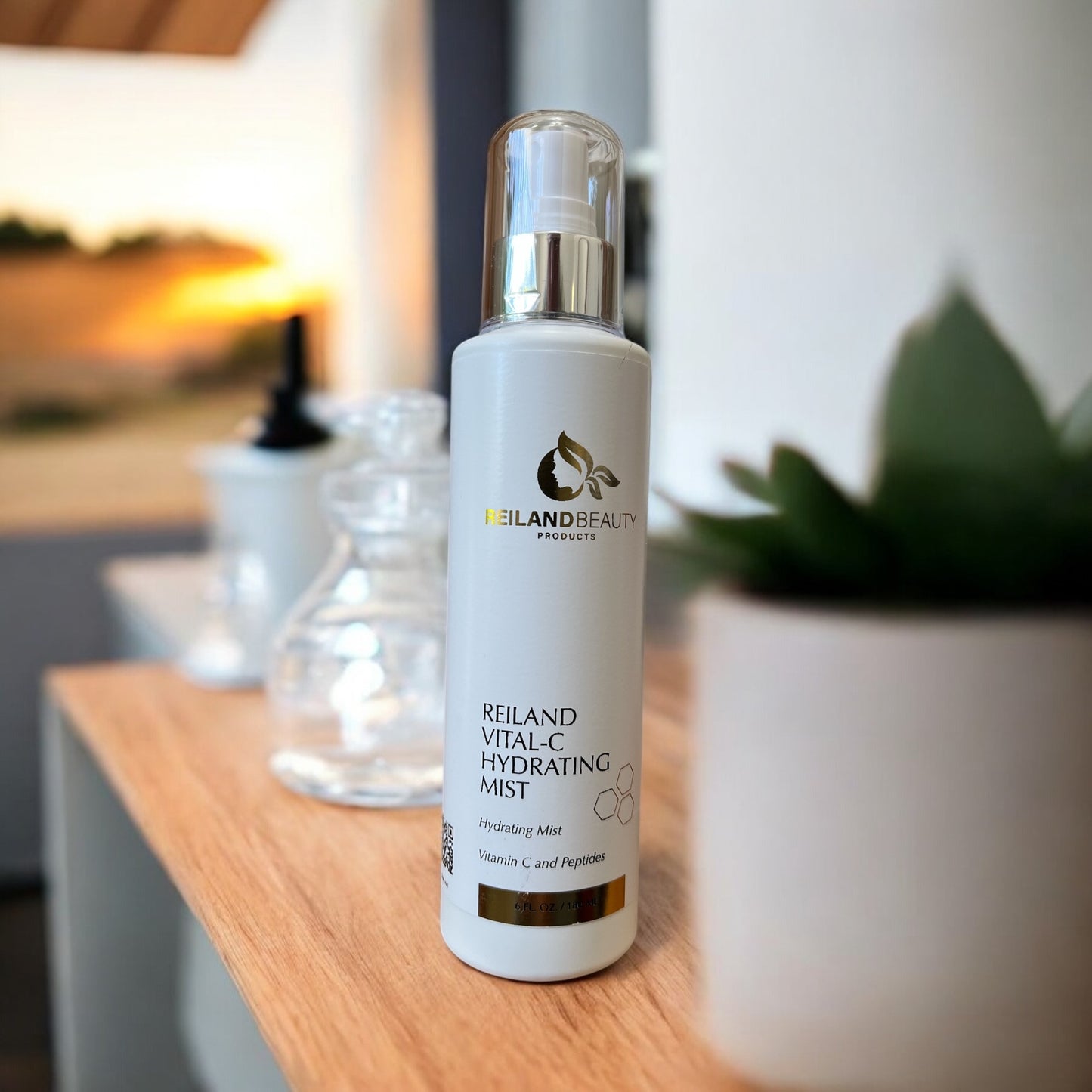 Reiland Vital-C Hydrating Mist – luxury Vitamin C face mist for hydration and collagen boost, displayed elegantly on a wooden surface with a soft-focus sunset in the background.